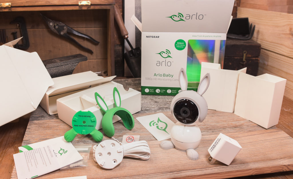 An Arlo baby monitor along with everything that comes in the box on a table