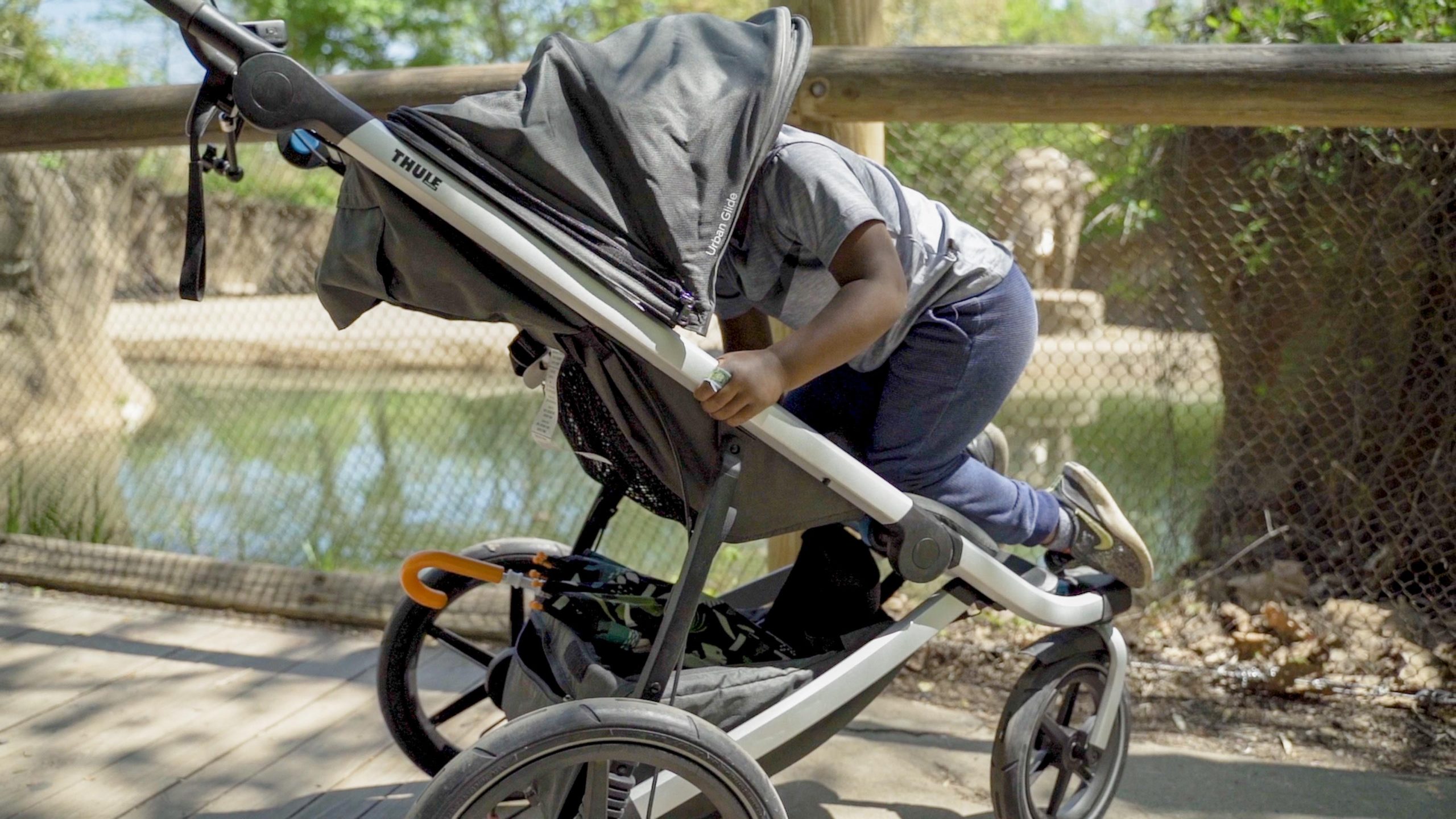 A kid climbing into a Thule jogging stroller