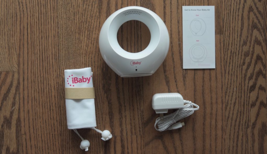 The iBaby Air unit with its instruction booklet, bag, and power cord on a hardwood floor